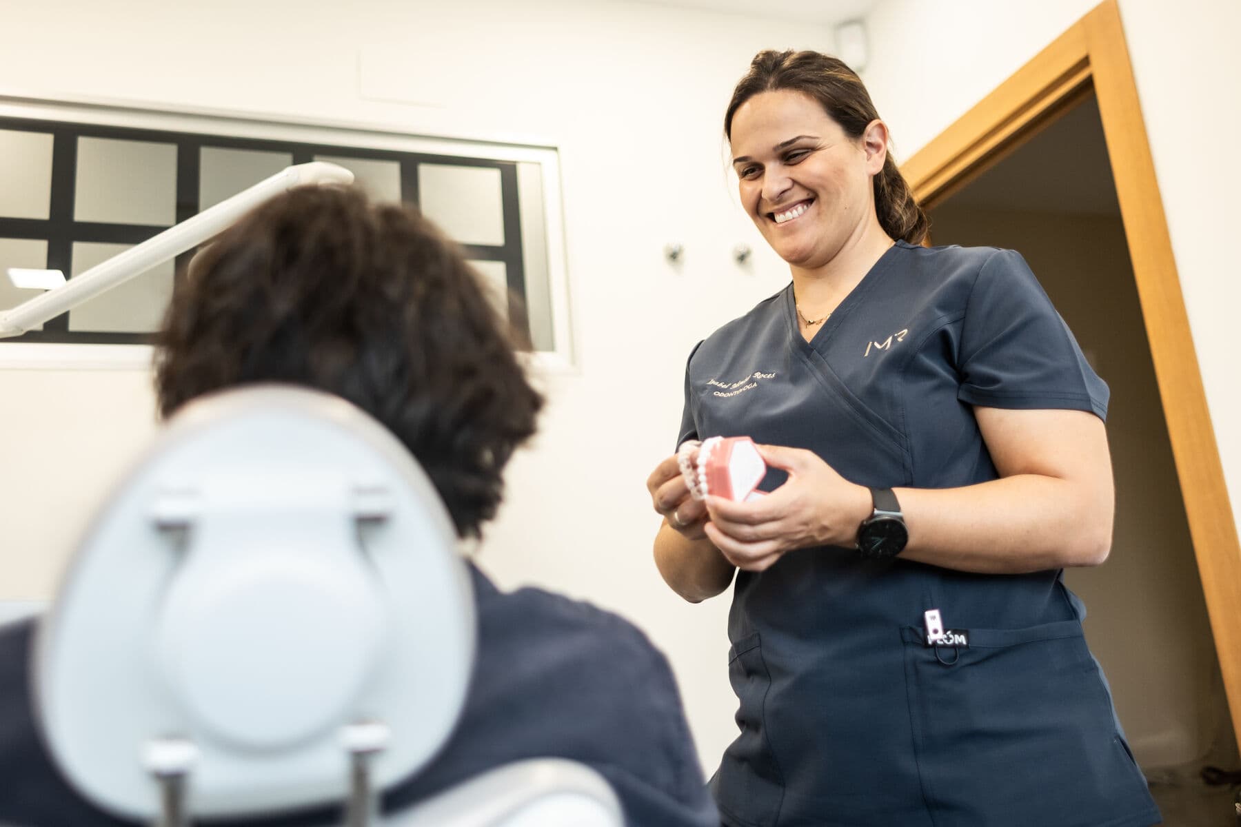 Isabel, sonriendo, explica con una maqueta de los dientes a quien está en el sillón